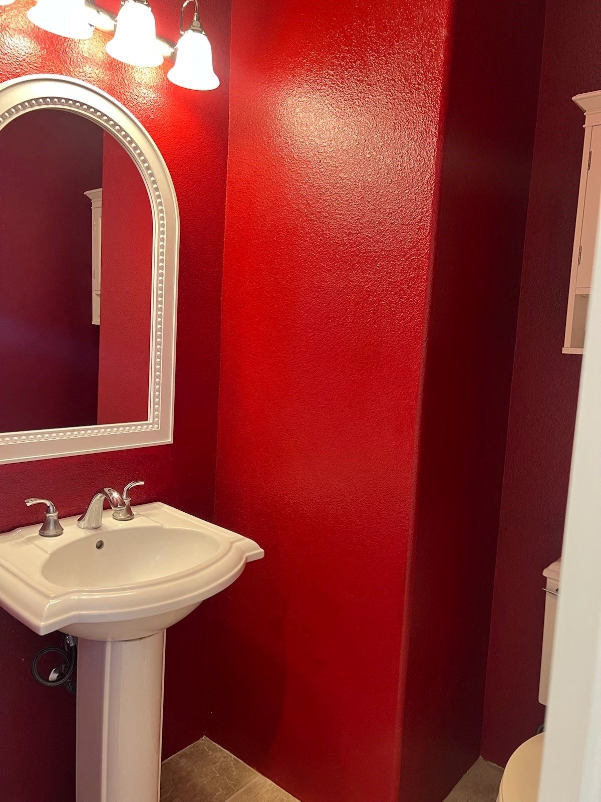 a red bathroom with a white sink and a mirror